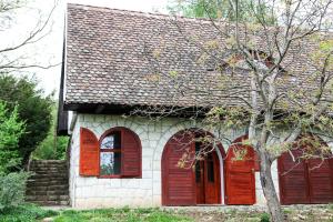 una casa con puertas rojas y un árbol en Myrtus Pince és Vendégház en Tarcal