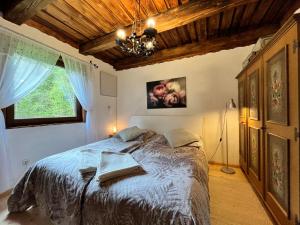 ein Schlafzimmer mit einem Bett mit einem Kronleuchter und einem Fenster in der Unterkunft Chalet Bodental 28 by Interhome in Bodental