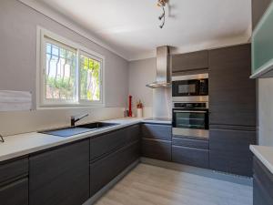 een keuken met grijze kasten, een wastafel en een raam bij Holiday Home Cascabelle by Interhome in Sainte-Maxime
