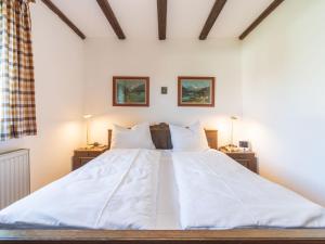 een groot bed met witte lakens en kussens bij Apartment Am Hohen Bogen-65 by Interhome in Kummersdorf