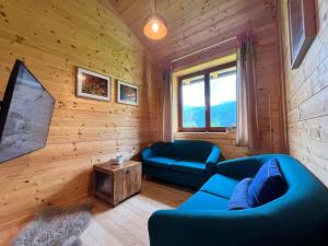 a living room with blue couches and a tv at Chalet Stressless by Interhome in Presseggen