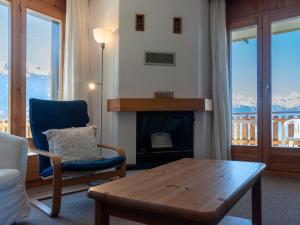 a living room with a fireplace and a table and a chair at Apartment Les Crêtes 1-4 by Interhome in Veysonnaz +27 photos
