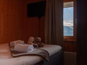 two teddy bears sitting on a bed looking out a window at Chalet Dolce Cabane by Interhome in Nendaz +40 photos