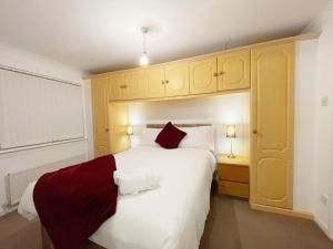 a bedroom with a large white bed with red pillows at Cozy Nights SVP Detached House in Nitshill