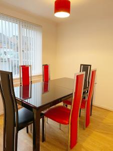 a dining room with a table and red chairs at Cozy Nights SVP Detached House in Nitshill