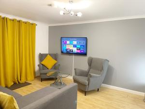 a living room with two chairs and a flat screen tv at Cozy Nights SVP Detached House in Nitshill