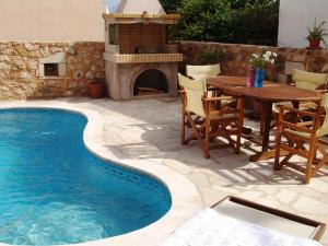 un patio con una mesa y una piscina en Ariadni Stone House with private pool, en Kolimvárion