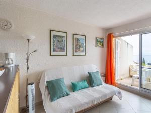 een woonkamer met een witte bank en blauwe kussens bij Apartment Les Pescadieres-4 by Interhome in Le Lavandou