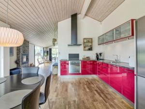 cocina con armarios rojos y mesa de comedor en Holiday Home Segelferd - 650m from the sea in NW Jutland by Interhome, en Løkken