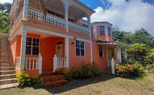 an orange house with a balcony and stairs at Cozy vacation retreat with free parking in Roseau