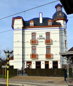 una mujer parada frente a un edificio blanco en De Torre en De Haan