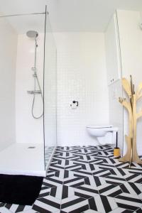 a bathroom with a shower and a black and white tile floor at Le Moulin Chambres hôtes in Montréal La Cluse