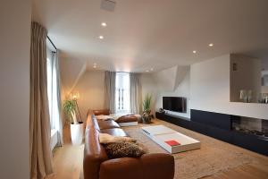 a living room with a leather couch and a tv at De Torre in De Haan