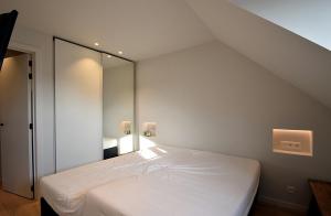 een slaapkamer met een wit bed en een spiegel bij De Torre in De Haan