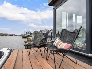 drie stoelen op een steiger naast het water bij Holiday Home Harboursuite incl- boot-2 by Interhome in Woudsend