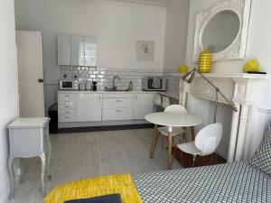 una cucina bianca con tavolo, tavolo e sedie di Belsize Park Boutique Accommodation a Londra