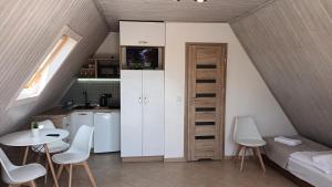 eine kleine Küche und ein Wohnzimmer mit einem Tisch und Stühlen in der Unterkunft Pensjonacik Ewa in Darłowo