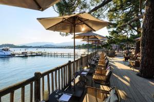 une rangée de chaises et de parasols à côté de l'eau dans l'établissement Grand Hôtel De Cala Rossa & Spa Nucca, à Porto-Vecchio