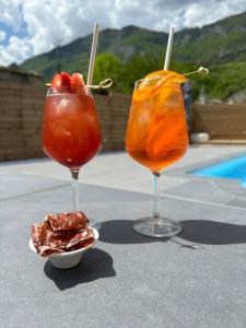 duas bebidas sentadas numa mesa ao lado de uma taça de fruta em L'instant d'un séjour em Le Guâ