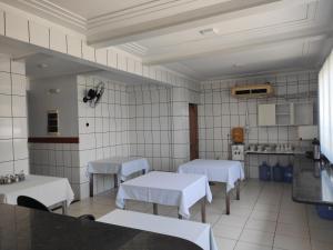 uma cozinha com mesas brancas e paredes de azulejos brancos em PREMIER HOTEL em Marabá