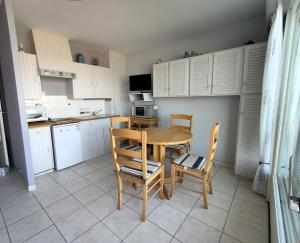 een keuken met een tafel en stoelen en een keuken met witte kasten bij Studio 2 Personnes -- Vue Port de Comberge ! in Saint-Michel-Chef-Chef
