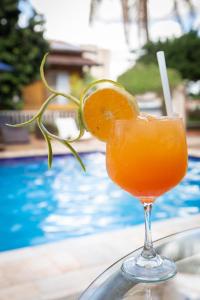 a glass of orange juice next to a pool at Pousada Shangrila in Ribeirão Preto