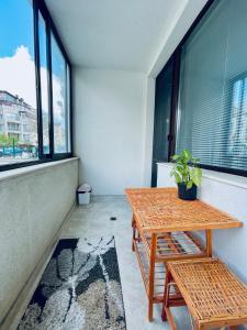 a balcony with a wooden table and bench and windows at Морски Бриз in Varna City