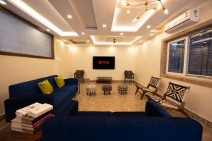 sala de estar con sofás azules y TV de pantalla plana en Lakeside Suites en Calcuta