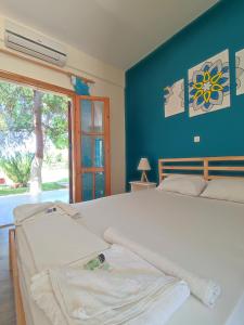 Filoxenia Apartments في Rizá: غرفة نوم بسرير ابيض بجدار ازرق