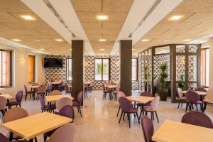 a dining room with tables and chairs and windows at Iberik Gran Balneario de Guitiriz in Guitiriz