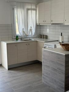 a kitchen with white cabinets and a sink and a window at Eleni's Village Suites in Klouvas