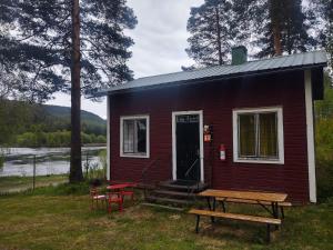 a red house with a picnic table in front of it at Selholmens Camping in Älvsbyn