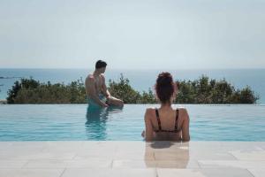 Un uomo e una donna seduti in piscina di Actea Seaview Villas I Free heated pool & 800m sea a Kíssamos
