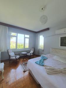 1 dormitorio con 1 cama, 2 sillas y ventanas en شقة اطلالة كاملة على مدينة بورصة مع مسبح وسط المدينة en Çekirge
