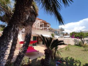 een huis met een palmboom en een rode schommel bij BILOCALE MAZZARELLI in Marina di Ragusa