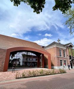 un edificio de ladrillo con un arco delante de él en Het Kostershuisje, en Nuenen