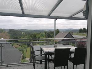 a table and chairs on a balcony with a view at 3-Raum Ferienwohnung in Willmersdorf - Thüringer Wald in Grossbreitenbach