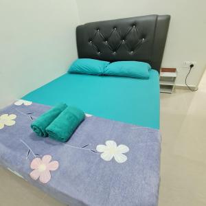 Una cama con una manta azul con flores. en OLIA MEDINA KERTEH 4 BILIK HOMESTaY, en Kampong Kemaman