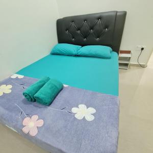 een bed met een blauwe deken met bloemen erop bij OLIA MEDINA KERTEH 4 BILIK HOMESTaY in Kampong Kemaman