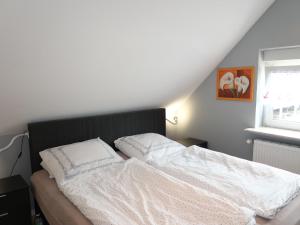 a bed with white sheets and pillows in a bedroom at Apartment Strandkorb by Interhome in Hooksiel