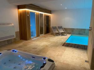 ein Badezimmer mit einer Badewanne und einem Pool in der Unterkunft Lush holiday home in Theux with heated indoor pool in Sprimont