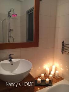 W łazience znajduje się umywalka, lustro i świece. w obiekcie Nandy's home w mieście Odza II
