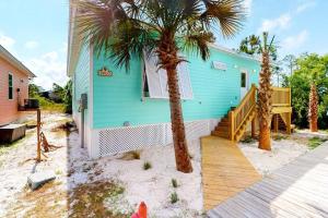 una casa azul con dos palmeras delante en Sea La Vie Beach Cottage 3b2b - 2 Pools, en Gulf Shores