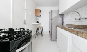 a white kitchen with a black stove top oven at Tabas - Lindíssimo apê 3 quartos na Lagoa - LG0006 in Rio de Janeiro