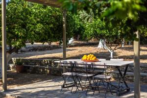 - une table avec des chaises et un bol d'oranges dans l'établissement Lemoni House, à Andros