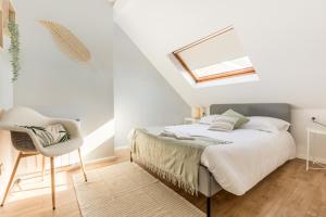 a white bedroom with a bed and a chair at Le Cottage de l'Hippodrome. in Lambersart