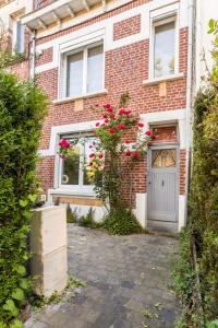 una casa di mattoni con una porta bianca e fiori rosa di Le Cottage de l'Hippodrome. a Lambersart