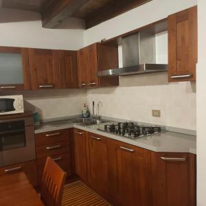 a kitchen with wooden cabinets and a stove top oven at Appartamento centro Lecco in Lecco