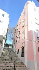 un edificio rosa con escaleras que conducen a él en Alfama Graça district typical & bright , 3 bedroom apartment with AC 1st floor en Lisboa