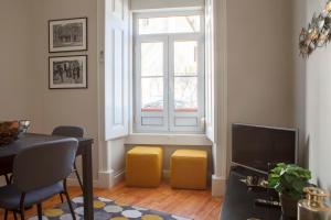 リスボンにあるAlfama Graça district typical & bright , 3 bedroom apartment with AC 1st floorの窓付きのリビングルーム、黄色いスツール2脚
